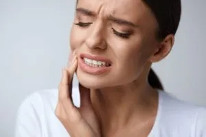 a woman holds her face in dental pain