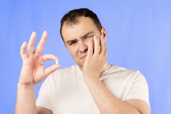 man in pain holding tooth